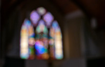 arched stained glass window in church sanctuary with blur effect