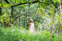 a young woman standing in a forest 