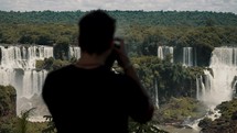 Man Taking Photos Of Iguazu Falls In Argentina - Medium Shot
