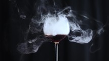 Glass filled with cola dark liquid and smoke with a black background