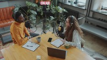 African American Man Giving Interview to Female Journalist in Podcast Studio
