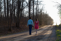 couple walking down a dirt road at sunset 