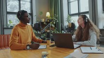 Black Podcast Host Interviewing Young Female Guest in Recording Studio
