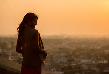Man standing on a balcony outside overlooking the city of Jaipur.