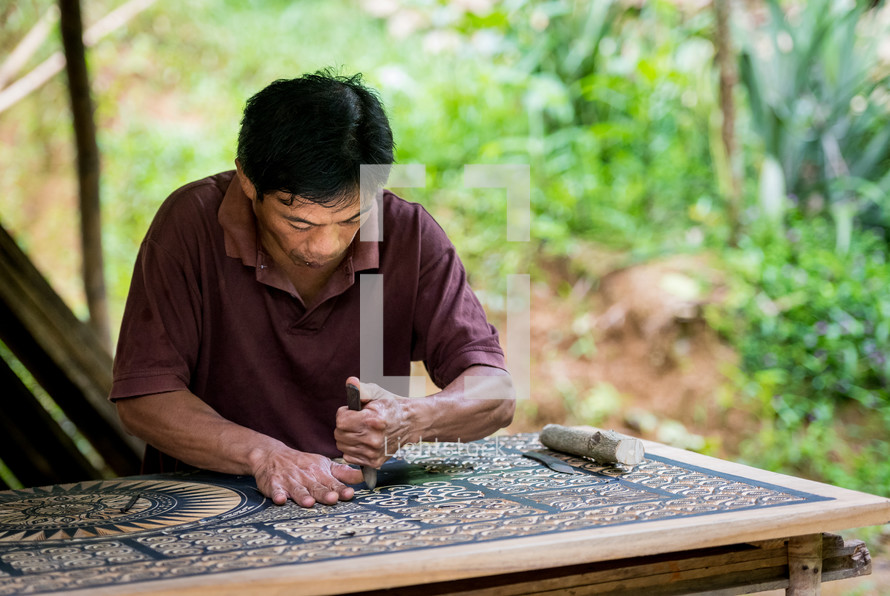 a man carving ornate detail into wood