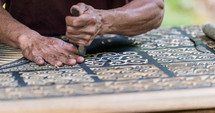 a man carving ornate detail into wood 