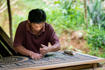 a man carving ornate detail into wood