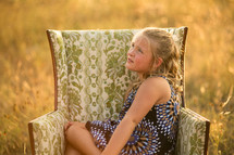 girl sitting in a armchair in a field