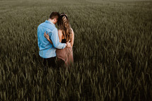 a couple snuggling in a field of wheat 