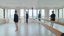 Young professional ballerina and danseur practicing classical ballet and discussing moves while choreographing performance in studio with mirror wall. Full shot
