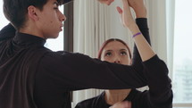 Young duet dancing with arms entwined while practicing contemporary dance in a studio. Handheld shot
