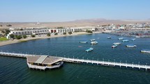 Aerial shot drone flies over pier at edge of boat marina in Paracas, Peru