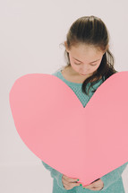 small girl holding a large paper heart 