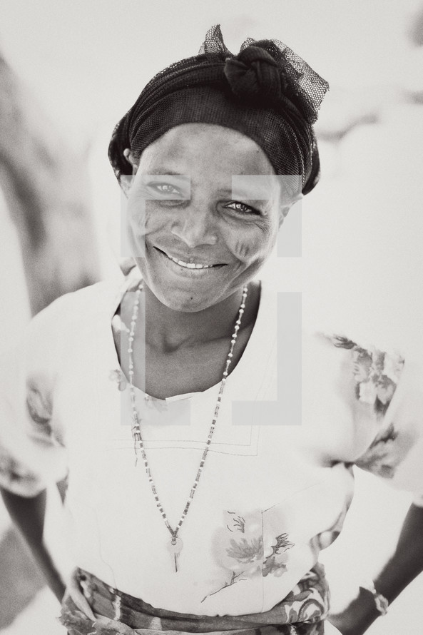 Smiling woman with head scarf and key necklace.