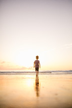 a toddler walking on a beach at sunset 