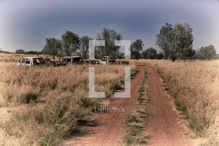 abandoned vehicles along a dirt road in Australia 