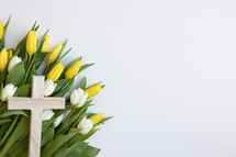 Cross on a bed of yellow and white tulips on white background 