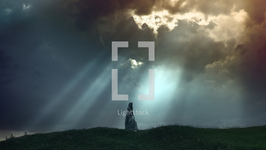 A Pilgrim silhouette on a hill with clouds and rays of light.
