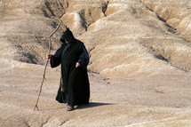 Hermit walking through the desert - copy space. Religious concept of enlightenment through fasting and prayer.
