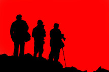 silhouettes of tourists in front of a red sky 