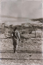 soldier with a gun walking through the desert 