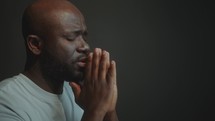 African American Man Holding Hands Together and Saying a Prayer