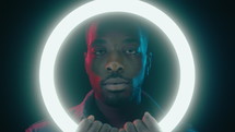 African American Man Posing with Ring Light in Dark Studio