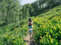 mother and son walking on a path through yellow flowers 