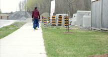 Man walking wheelbarrow to construction site - wide shot