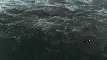 drone flying over surfer looking down into crashing waves in the ocean