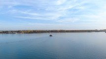 Ferry Boat Cruising And Approaching Towards Riverside At Daytime. wide aerial drone