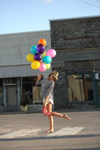 teen girl carrying balloons and her shoes 