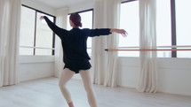 Young inspired ballerina doing arabesque, passe and pirouette while performing graceful dance in studio. Full shot
