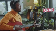 Musician Singing and Playing Guitar during Radio Show with Female Host
