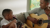 Happy father and son playing guitar. Family, parenthood, music and spending time together concept 