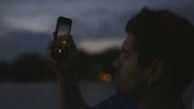 Man on a boat taking picture at Sunset with his cellphone 