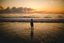 toddler silhouette standing in the ocean 
