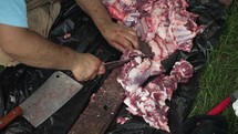 Hands of middle eastern, Muslim men with knife cutting sheep meat preparing for Islamic religious holiday Eid Al Adha or Eid Al Fitr in cinematic slow motion.
