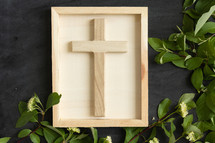 wood cross on chalkboard with border of green leaves