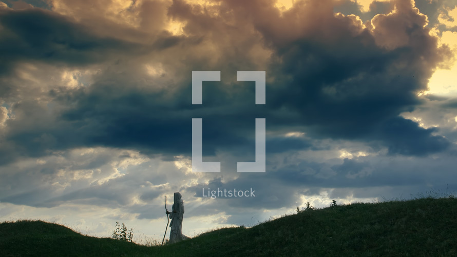 A Pilgrim silhouette on a hill with dramatic clouds
