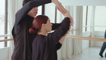 Young duet performing graceful and smooth arm movements during contemporary improvisation in a dance studio
