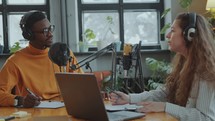 Young Man and Woman Hosting Podcast Together in Recording Studio
