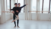 Young ballet partners practicing fish dive lift gracefully white rehearsing in a modern dance studio. Full length shot with copy space
