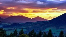 Sunset in an idyllic hilly landscape, beautifully colored clouds, summer rural landscape