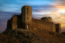 Fortress on the mountain with red cross flag. Biblical concept of the tower of escape.

