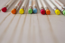 rainbow colored erasers of pencils spaced apart at the top 