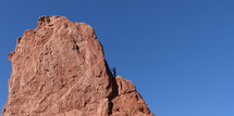 rock climber on rugged red rock against blue sky
