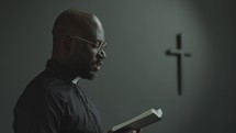 African American Priest Reading Bible in Church during Liturgical Service
