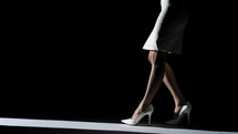 Woman walking on heels with dark background 