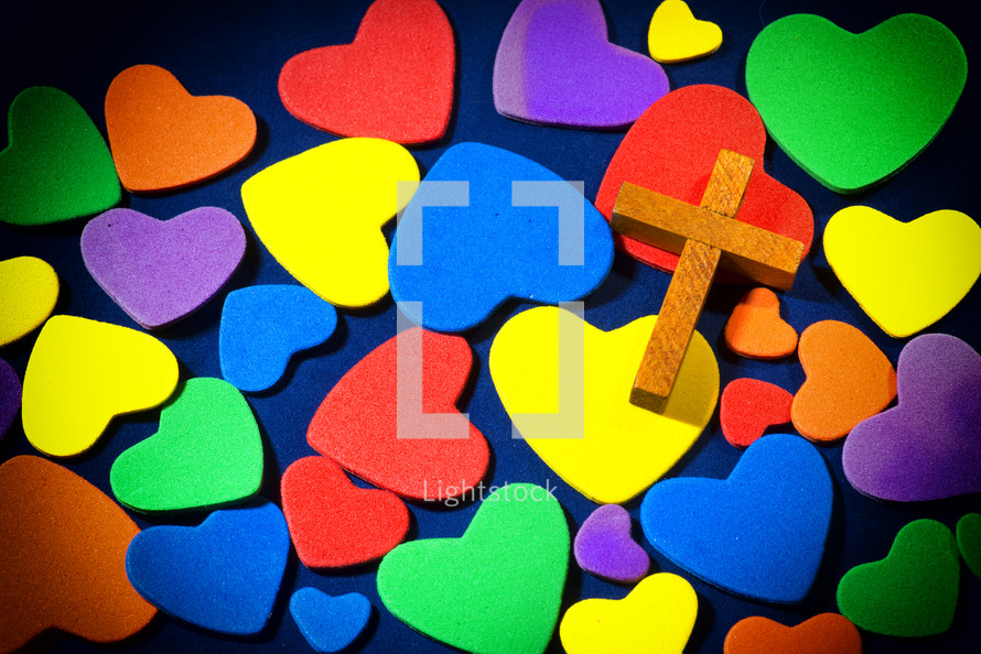 Wooden cross on colorful hearts.